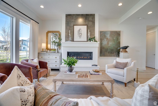 living room featuring recessed lighting, light wood-type flooring, and a large fireplace