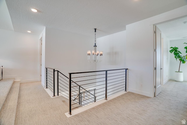 corridor featuring a chandelier, baseboards, carpet, and an upstairs landing