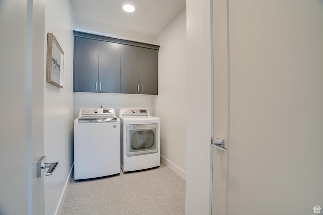 laundry area with baseboards, cabinet space, and washer and clothes dryer