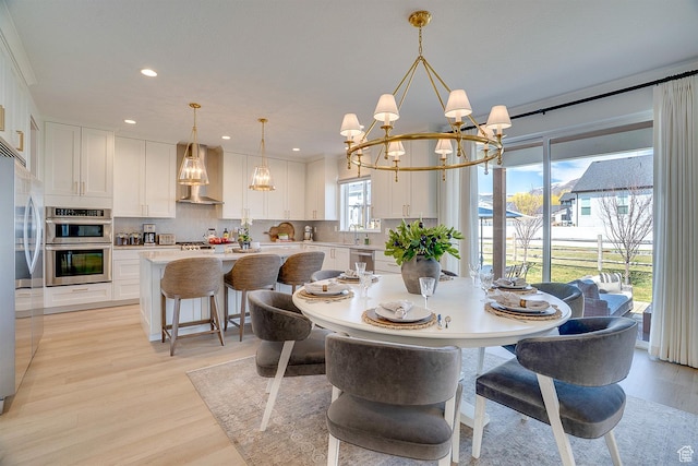 dining area featuring light wood-style floors, a notable chandelier, and recessed lighting