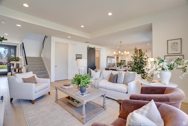 living area with a barn door, recessed lighting, stairs, light wood finished floors, and a notable chandelier