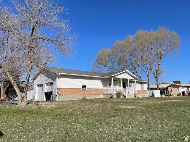 view of front of house featuring an attached garage, covered porch, a front lawn, and brick siding