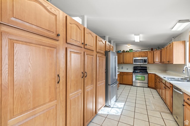 kitchen with vaulted ceiling, light countertops, light tile patterned flooring, stainless steel appliances, and a sink