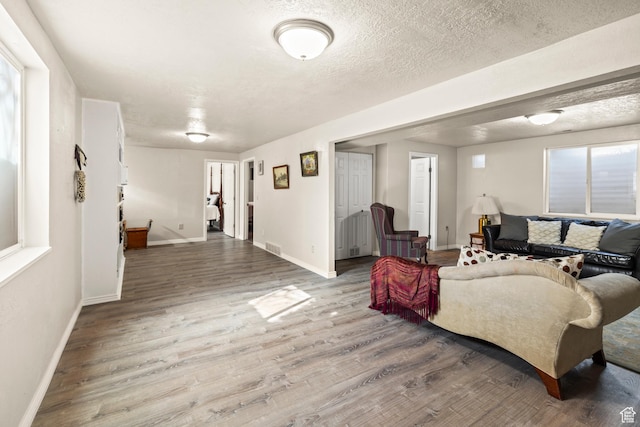 living room with baseboards, a textured ceiling, and wood finished floors