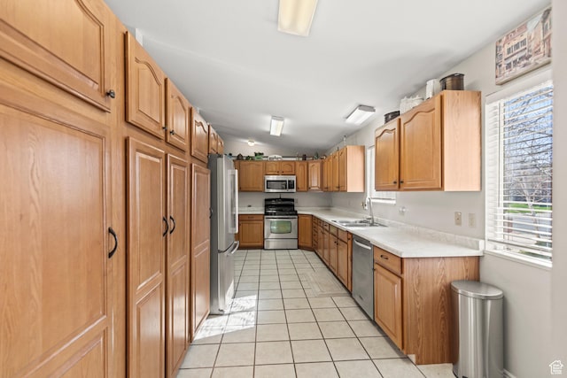 kitchen featuring light tile patterned floors, a sink, light countertops, appliances with stainless steel finishes, and vaulted ceiling