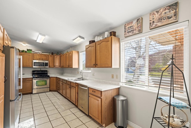 kitchen featuring vaulted ceiling, appliances with stainless steel finishes, light tile patterned flooring, light countertops, and a sink