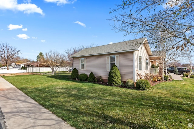 view of home's exterior featuring a yard, fence, and roof with shingles