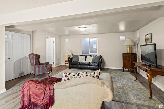 living room featuring visible vents, baseboards, and wood finished floors