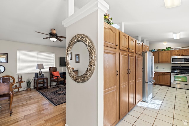 kitchen with light countertops, a ceiling fan, brown cabinets, light wood finished floors, and stainless steel appliances