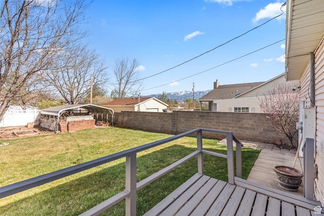 wooden terrace featuring a yard, a carport, a fenced backyard, and a mountain view