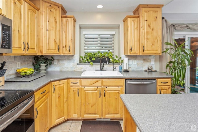 kitchen featuring decorative backsplash, a sink, light tile patterned floors, and appliances with stainless steel finishes