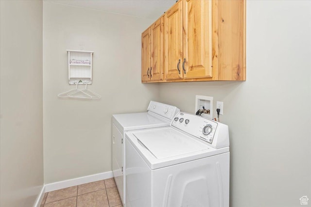 washroom featuring cabinet space, light tile patterned floors, washer and clothes dryer, and baseboards