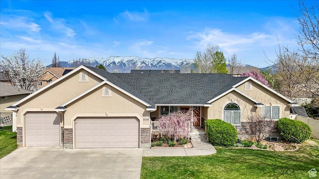 ranch-style house with a garage, a mountain view, stucco siding, stone siding, and driveway