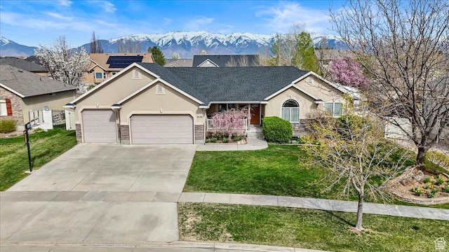 ranch-style home featuring a mountain view, stucco siding, a front yard, an attached garage, and concrete driveway