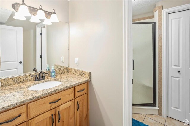 bathroom featuring tile patterned floors, vanity, and a stall shower