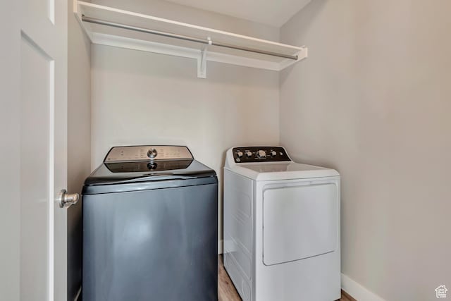 laundry room with washing machine and clothes dryer, wood finished floors, and laundry area