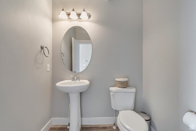 bathroom with baseboards, a sink, toilet, and wood finished floors