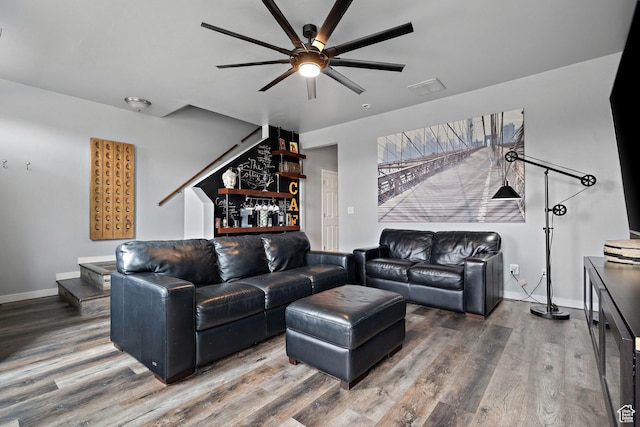 living area with stairway, visible vents, a ceiling fan, and wood finished floors