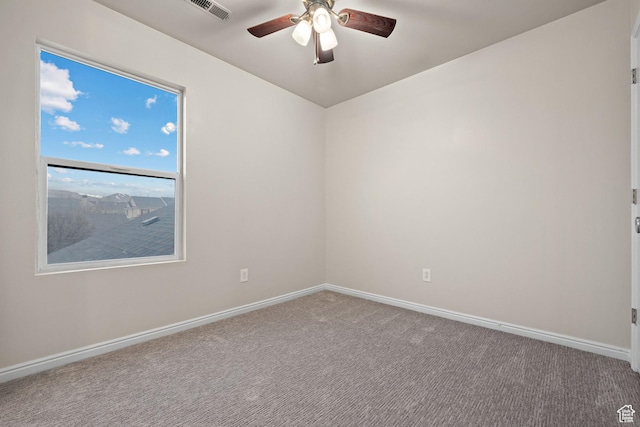 carpeted empty room with visible vents, baseboards, and ceiling fan
