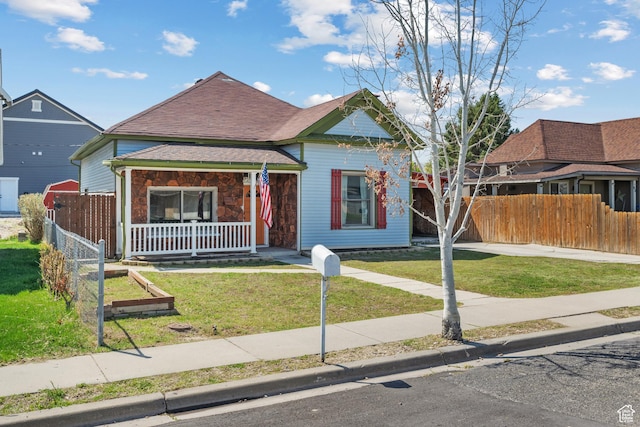 view of front facade featuring a porch, a front yard, and fence