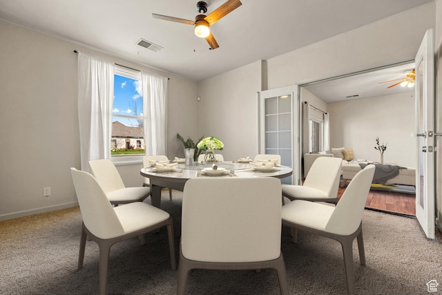 dining area featuring light colored carpet, baseboards, a ceiling fan, and visible vents