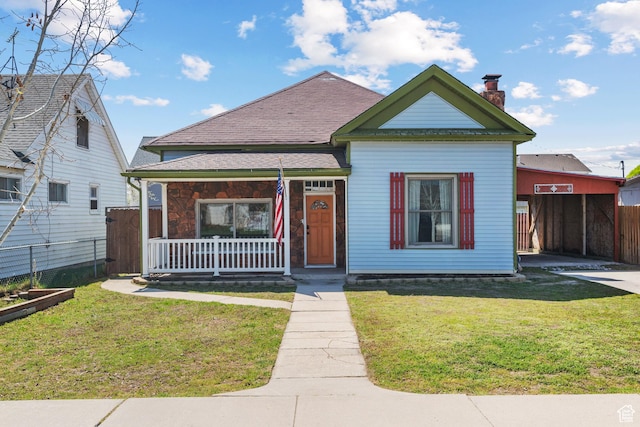 bungalow featuring a front yard, a shingled roof, covered porch, a chimney, and fence