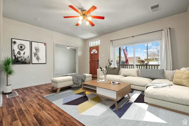 living room featuring visible vents, baseboards, a ceiling fan, and wood finished floors