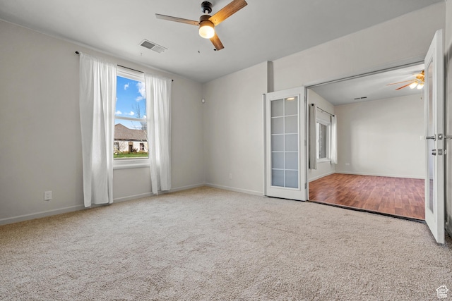 carpeted spare room featuring visible vents, baseboards, a ceiling fan, and french doors