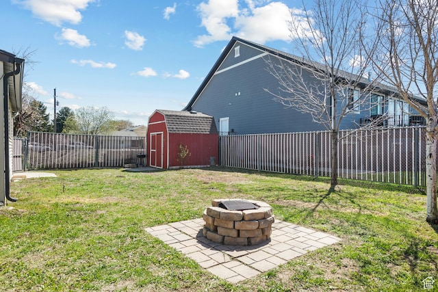 view of yard with a storage shed, an outbuilding, a fenced backyard, and an outdoor fire pit
