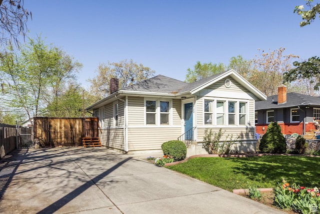 3752 S Mccall St E, South Salt Lake, UT 84115 - bungalow-style house featuring entry steps, a chimney, fence, a front lawn, and driveway