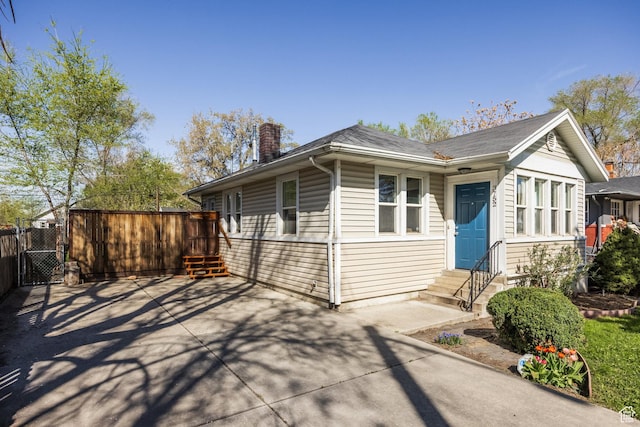 3752 S Mccall St E, South Salt Lake, UT 84115 - view of front of home featuring entry steps, a chimney, fence, concrete driveway, and a gate