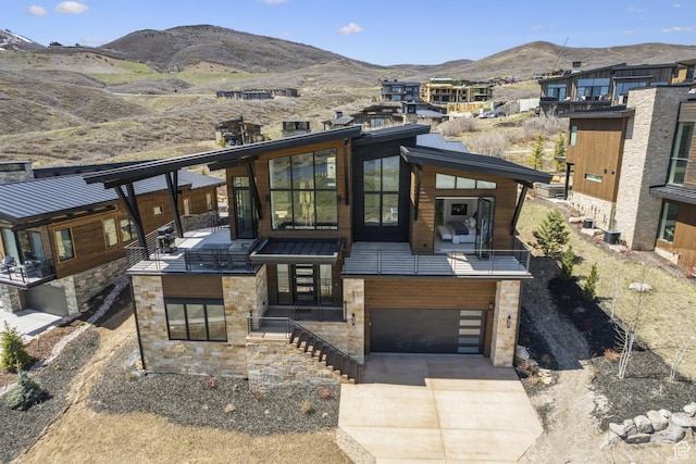 view of front facade featuring a mountain view, driveway, stone siding, a garage, and a standing seam roof