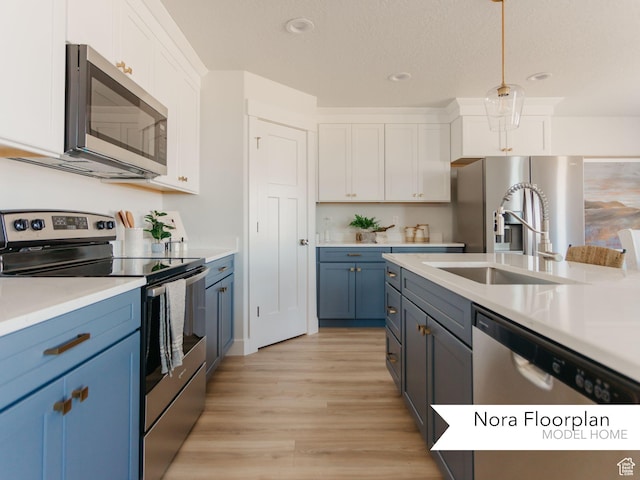kitchen featuring light countertops, white cabinetry, stainless steel appliances, light wood-style flooring, and blue cabinetry