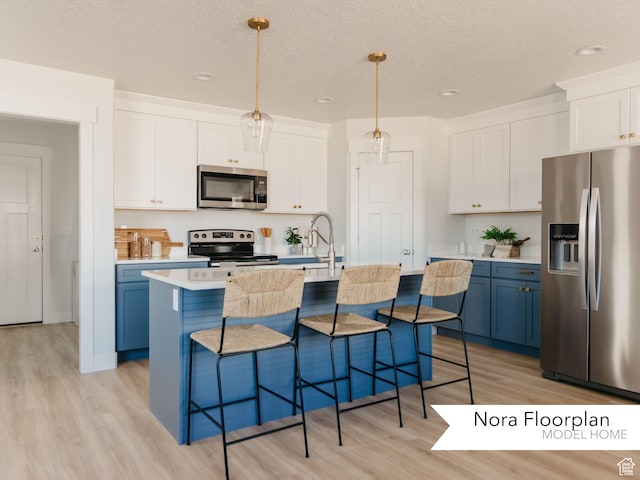 kitchen featuring light countertops, light wood-style flooring, appliances with stainless steel finishes, and a kitchen bar