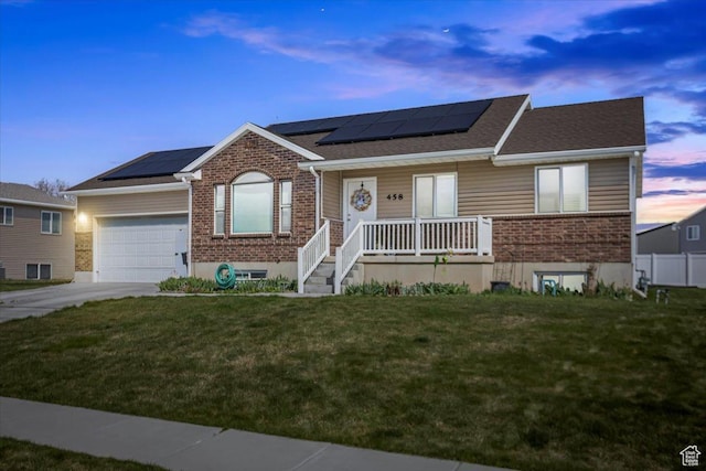 ranch-style home with brick siding, a yard, covered porch, and a garage