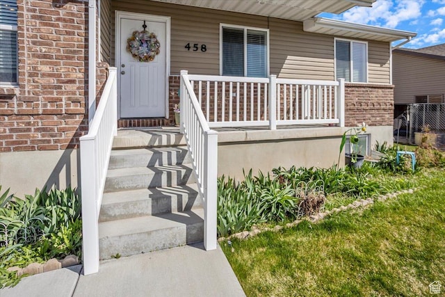 entrance to property featuring brick siding and covered porch