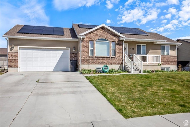 ranch-style home featuring driveway, an attached garage, a front lawn, brick siding, and roof mounted solar panels