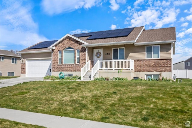 ranch-style home featuring a garage, a front yard, brick siding, and covered porch