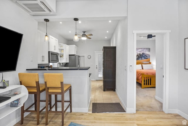 kitchen featuring ceiling fan, white cabinets, dark countertops, stainless steel appliances, and light wood finished floors