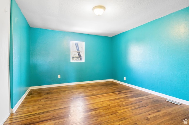 unfurnished room with visible vents, baseboards, and wood finished floors