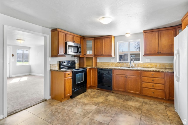kitchen with brown cabinets, a sink, and black appliances