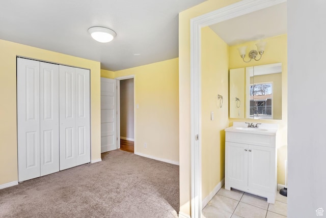 bedroom featuring baseboards, light carpet, a closet, and a sink