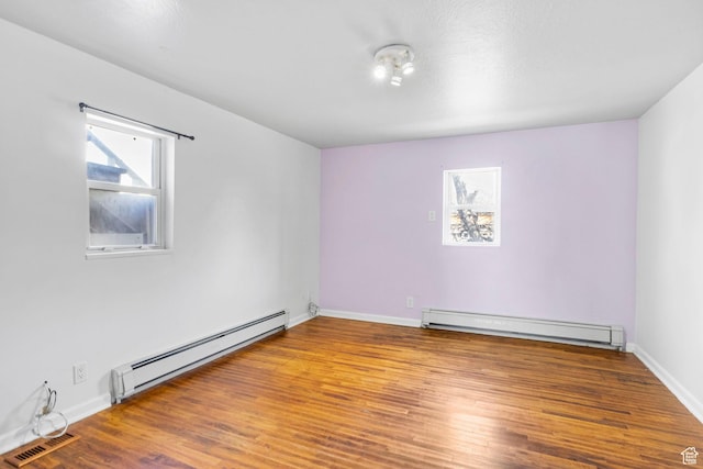 unfurnished room with visible vents, a baseboard radiator, wood finished floors, and baseboards