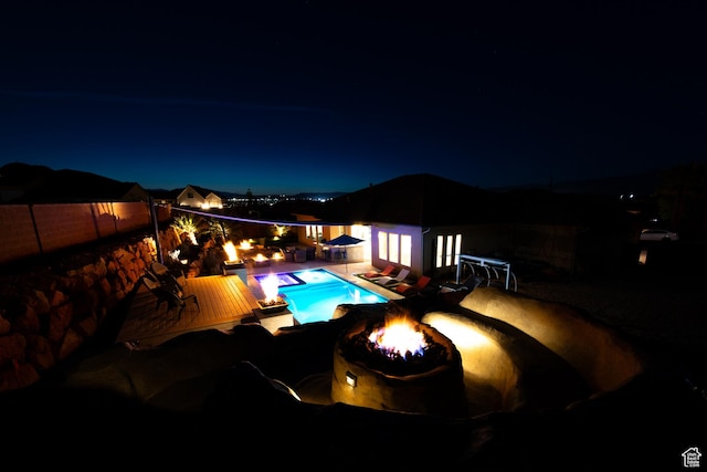 pool at night with a fenced in pool, a patio, and a fenced backyard