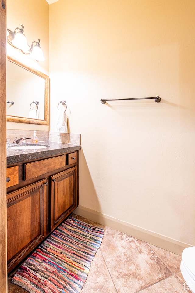 bathroom featuring toilet, tile patterned floors, baseboards, and vanity