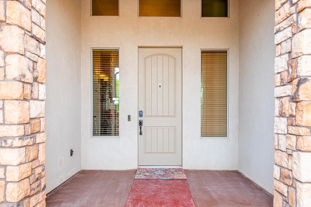 doorway to property featuring stucco siding and stone siding