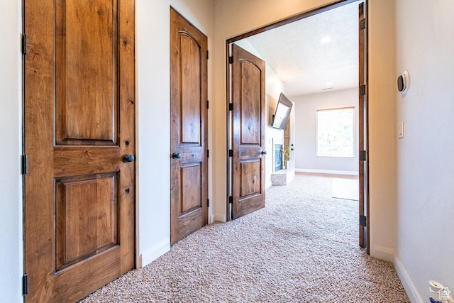 hallway featuring baseboards and carpet floors