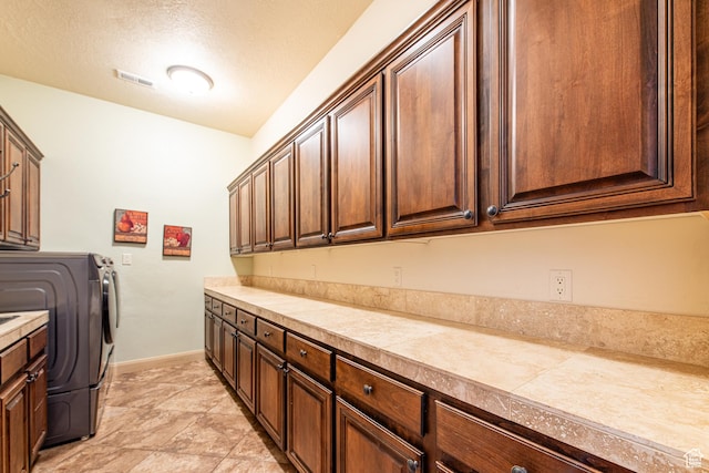 washroom with cabinet space, visible vents, baseboards, and a textured ceiling