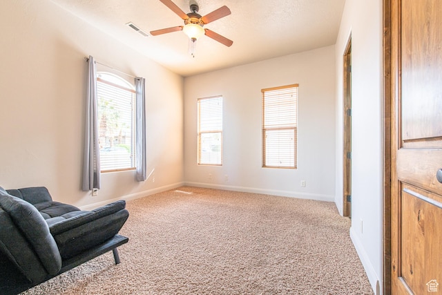living area featuring light carpet, visible vents, baseboards, and ceiling fan
