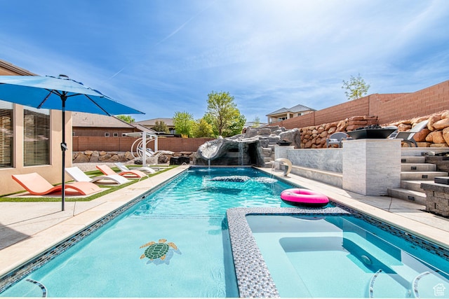 view of swimming pool featuring a pool with connected hot tub, a patio, and a fenced backyard